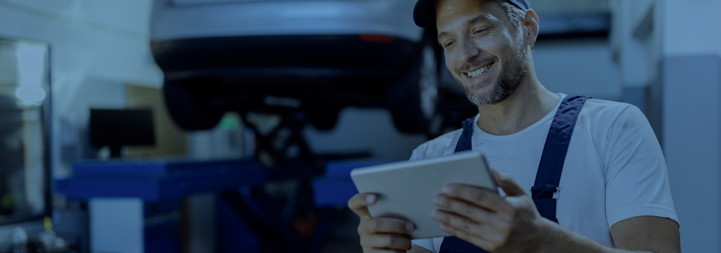 Usměvavý mechanik v dílně, který se zřejmě přihlásil k odběru newsletteru pomocí svého tabletu